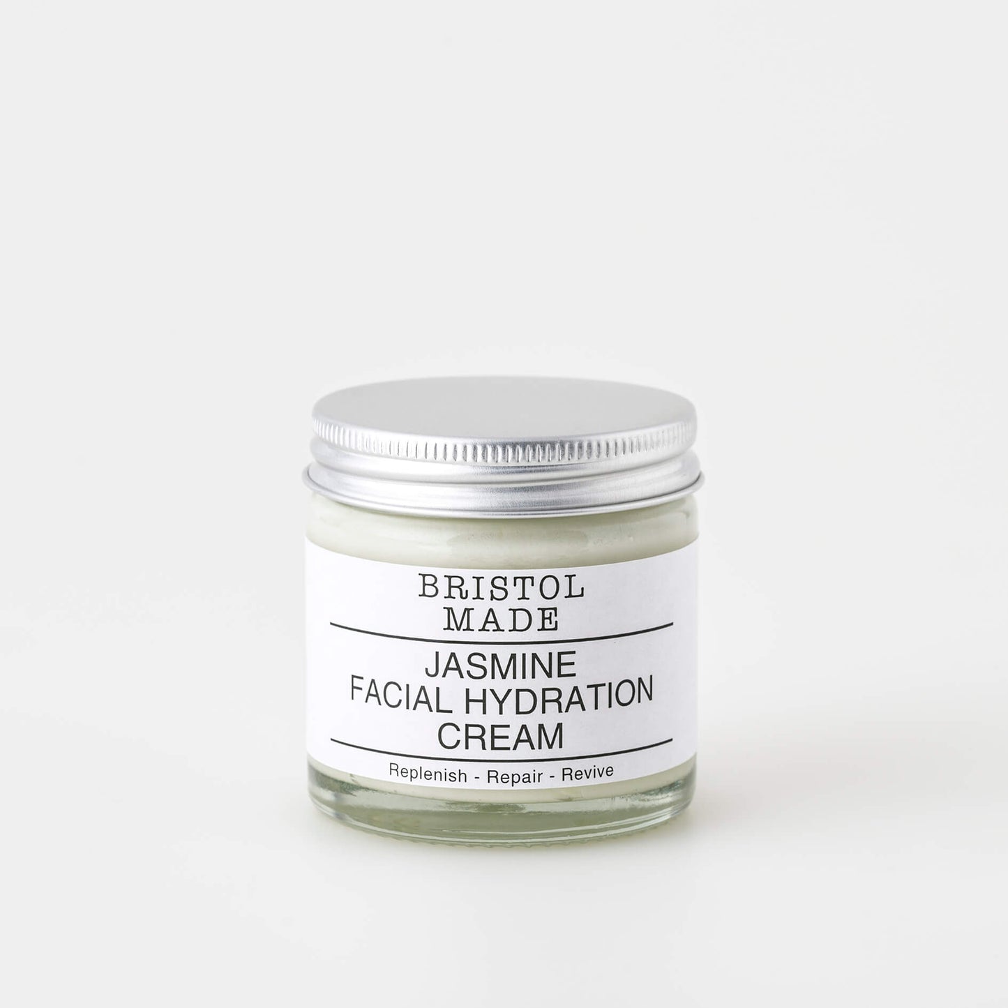 A 60ml clear glass jar of Bristolmade jasmine face cream, featuring a white label with black text, highlighting its vegan ingredients. 