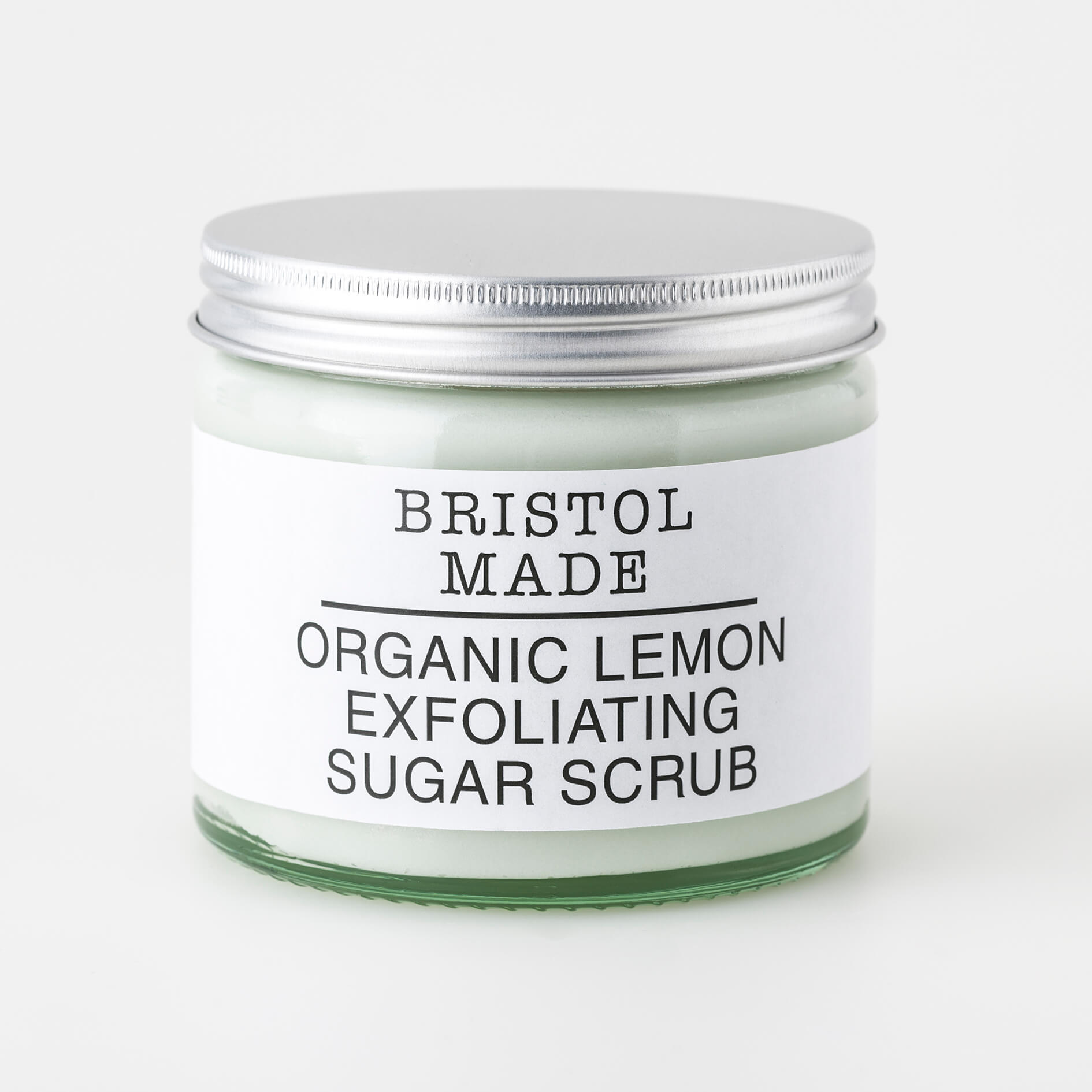 image of a Bristolmade body scrub, highlighting its rich ingredients and exfoliating particles. Packed in an eco friendly, 250ml clear glass jar, with a clear label detailing its rejuvenating and nourishing properties. 