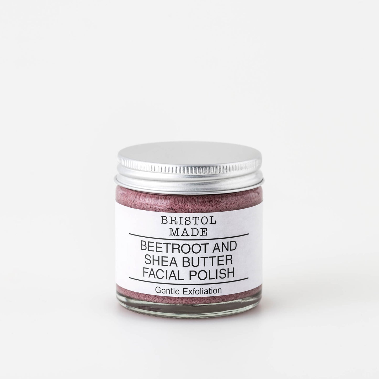 Photo of Bristolmade exfoliating face scrub, showing the  pink blend of natural ingredients and gentle exfoliating particles. Packaged in a 60ml clear glass jar, with a white label, clearly indicating the products purpose and benefits. 