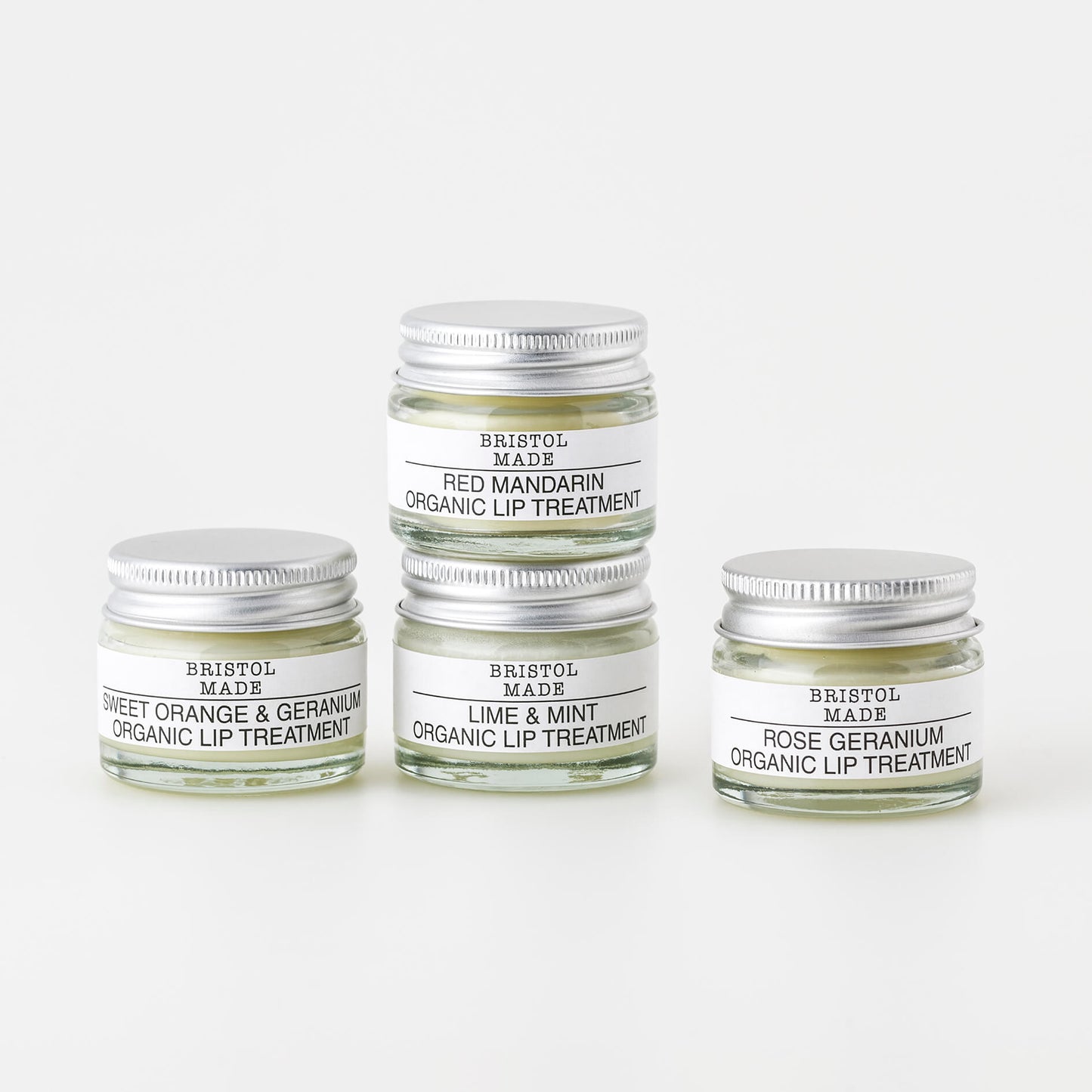 an image of four different Bristolmade lip balms, in 15ml clear glass jars, with white labels and black text, showing the different scents and ingredients of each product.