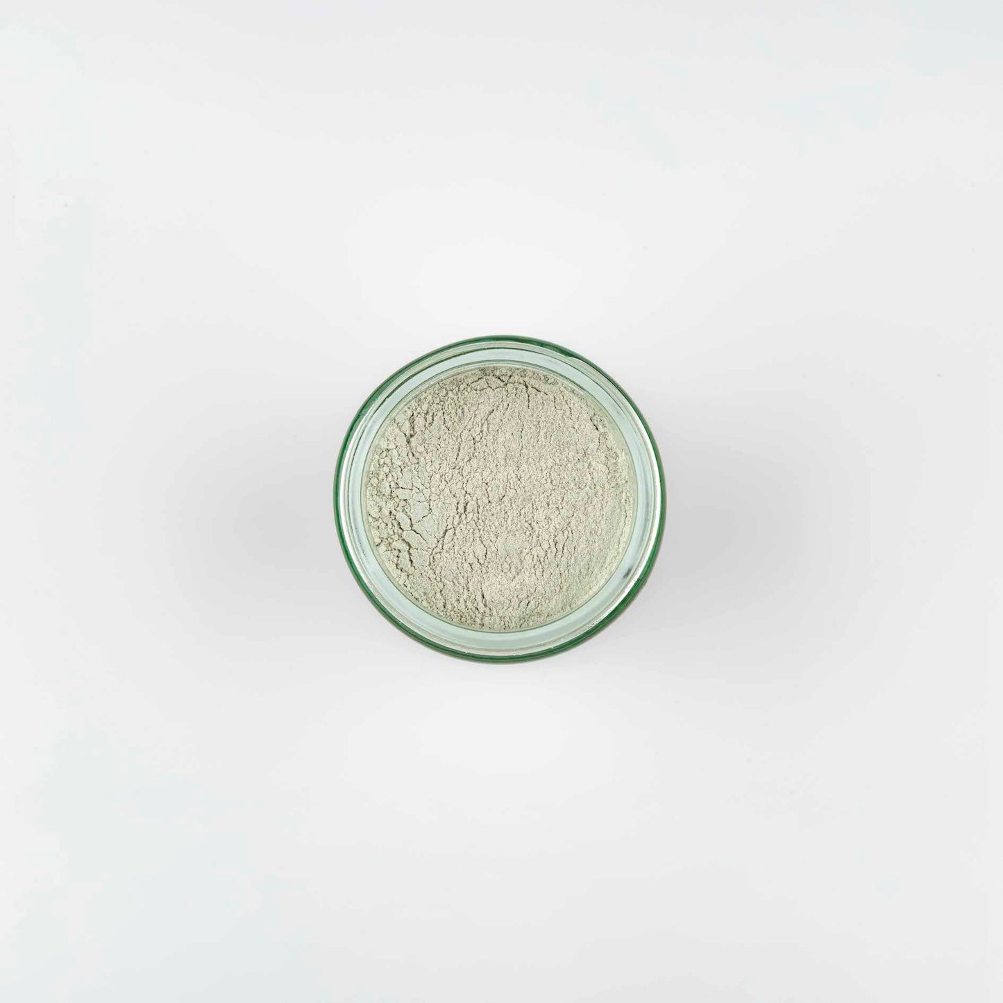 photo of the top view of a pale green powder, shows the fine particles, in a clear glass jar.