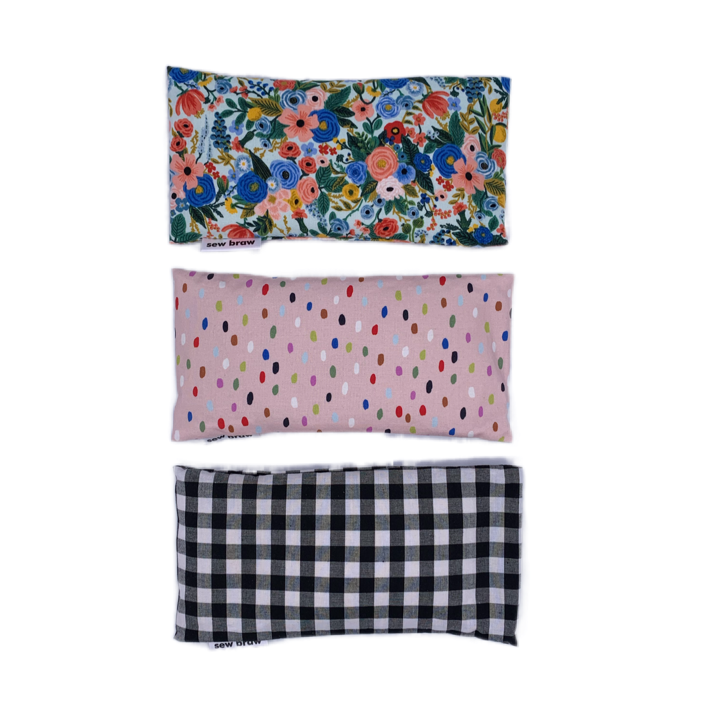 Photo of three lavender eye pillows, one floral, a pink with various coloured spots and a black and white check, on a white background